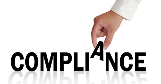 Compliance related words written wood blocks sitting on a wood surface in front of a defocused background. Compliance concept.