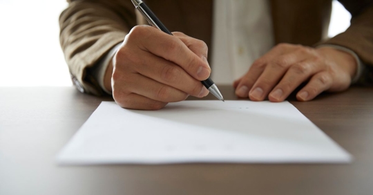 Rental agreement form with signing hand and pen.