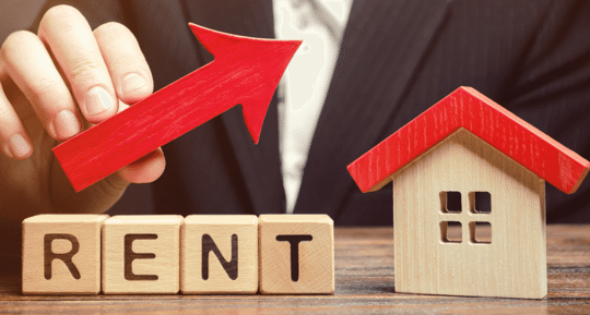 Wooden Toy House and Blocks Spelling Rent and an arrow going up signifying raising prices