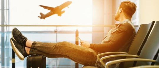man sitting in airport watching planes