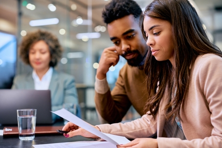 Young professionals analyzing paperwork during a meeting.